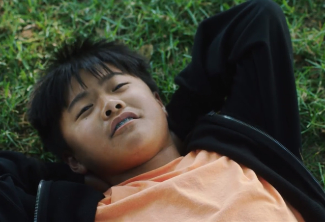 A young boy lays in grass.