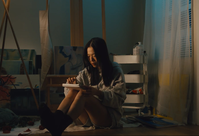 A woman sits in an art studio, sketching. 