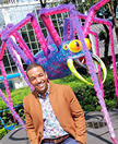 Photo of Lawrence Hall smiling in front of a colorful spider statue