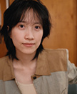 Photo of Yipu Su looking straight ahead and wearing a brown and gray collared jacket.