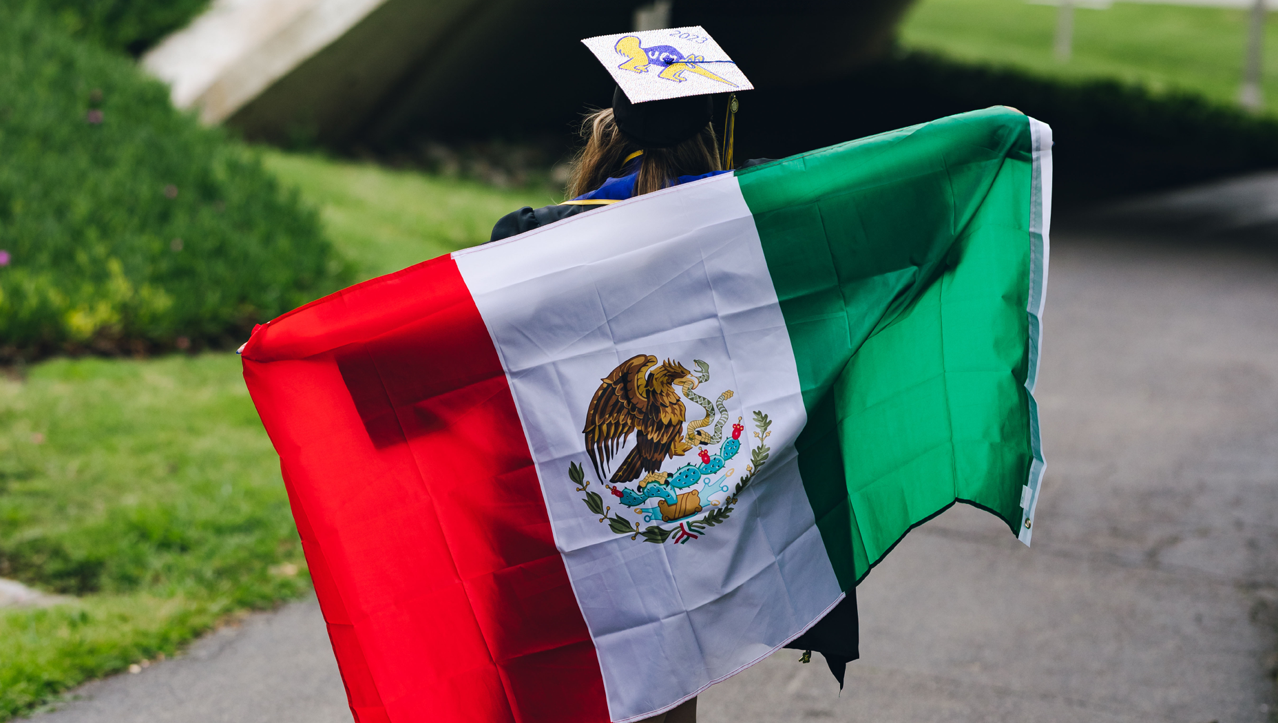 Jessica Ortiz holding a Mexican flag across her back as she walks away from the camera.