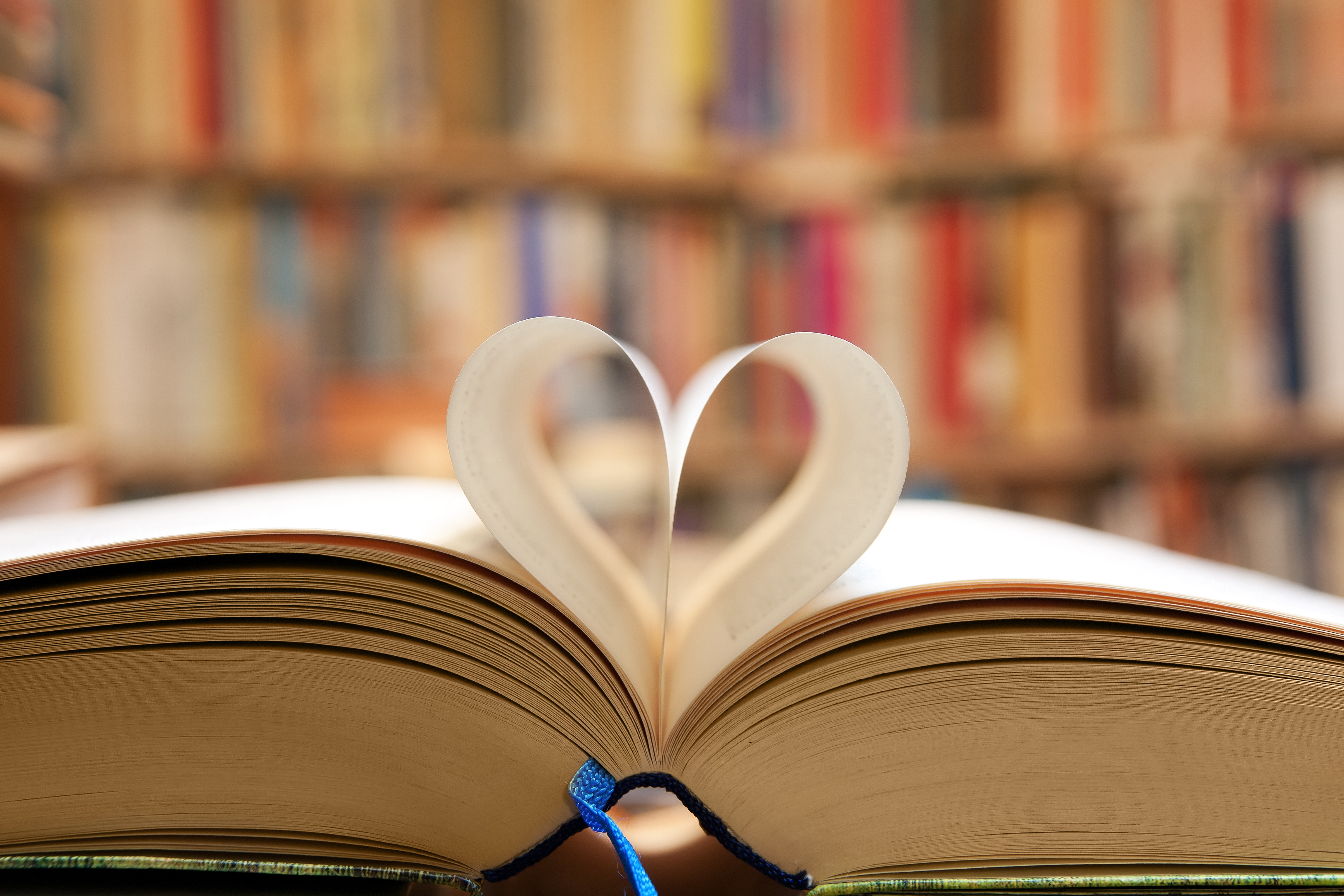 A picture of a book and pages forming a heart. 