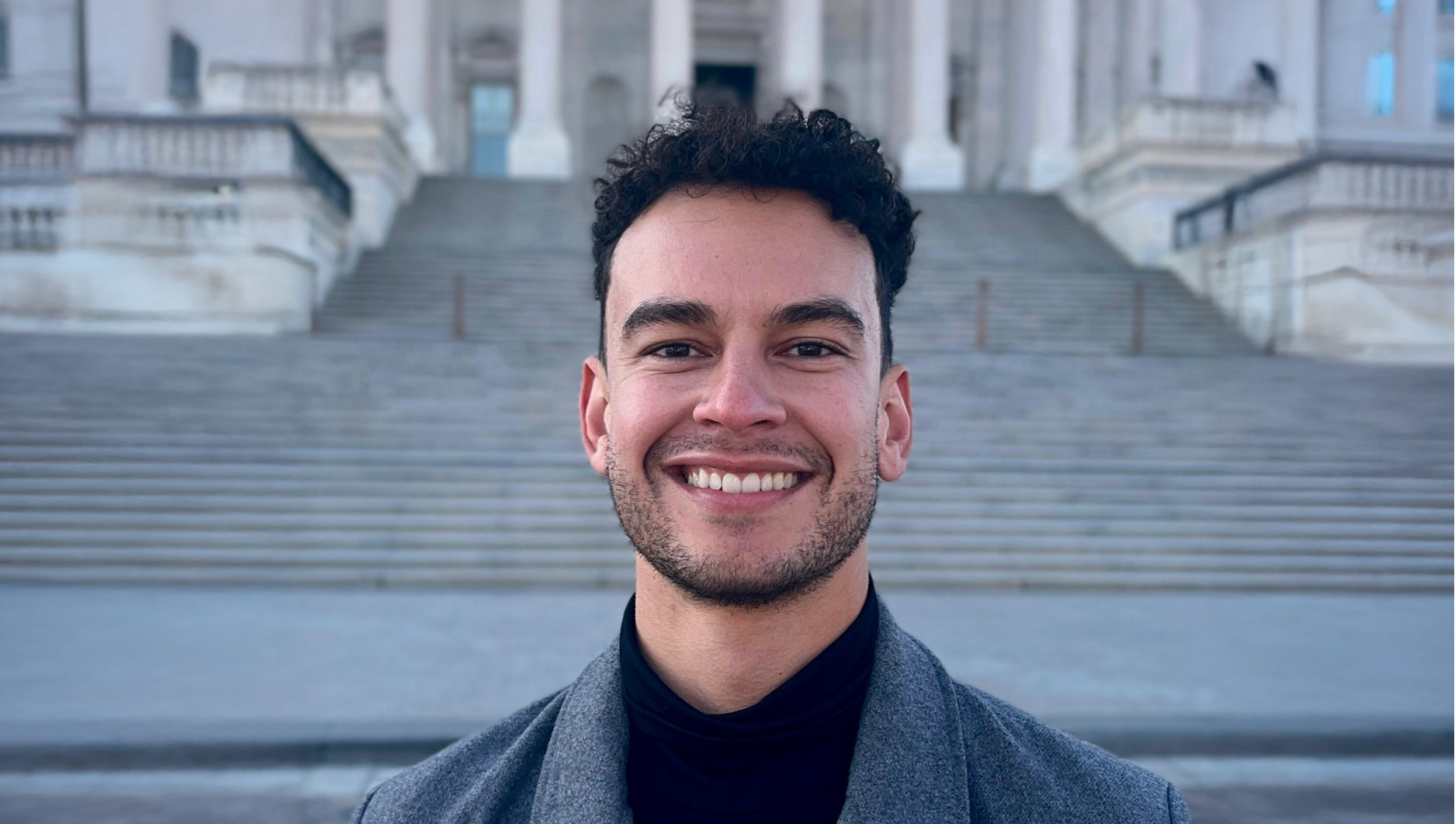 Headshot of Javier Burdette standing outside in front of stairs.