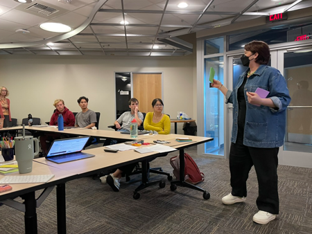 A woman stands in front of a classroom.