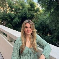 Blonde woman wearing green top and trees in the background
