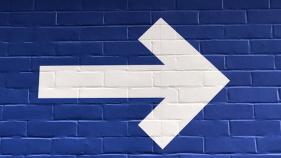 white arrow poining to the left painted on blue brick