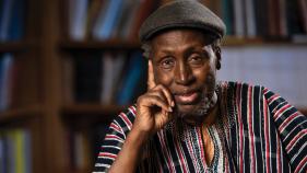 Ngũgĩ wa Thiong’o siting in front of a bookshelf