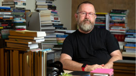 A photo of Jonathan sitting at his desk surrounded by books.