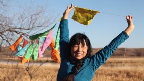 Wang Ping in field with prayer flags