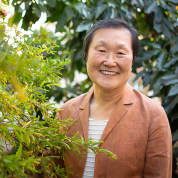 Carol Choi smiling next to a bush