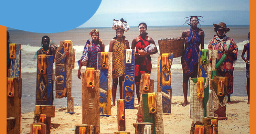 A group of people in traditional African outfits stand on a beach.