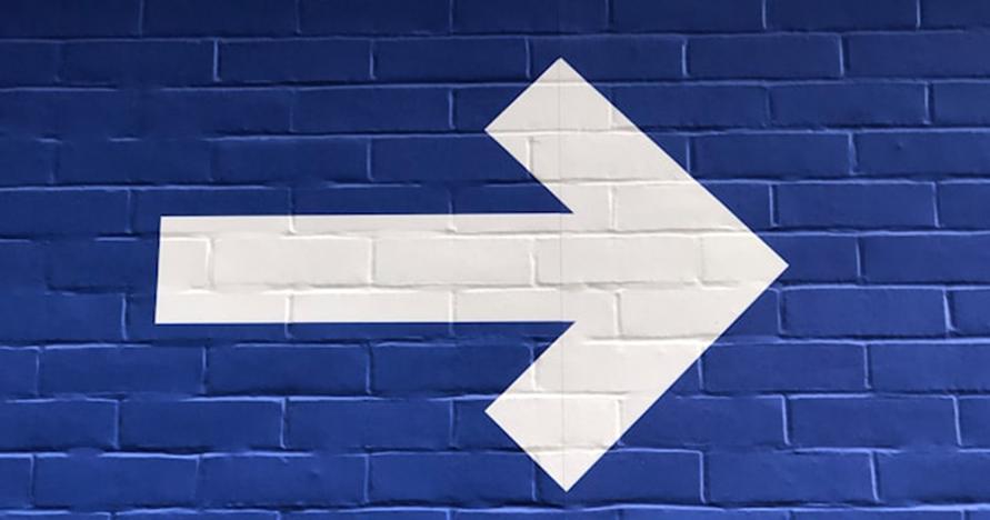 white arrow poining to the left painted on blue brick