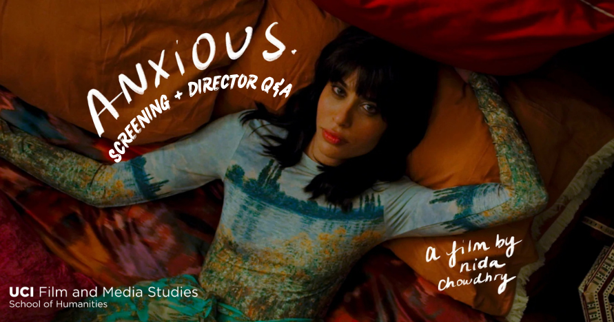 A still from the film ANXIOUS., showing the character Ruby, wearing a color dress, laying in a bed.