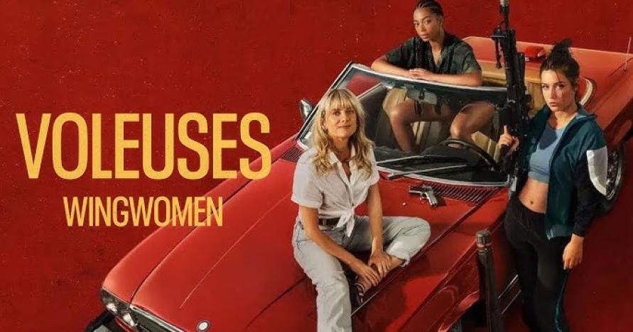 Three women smirking eith one holding a weapon