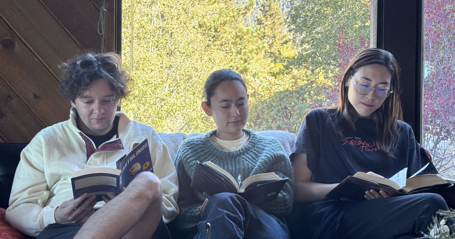 Herschel Uchitel, Zoe Adams, Emma Boyles sitting and reading together on a couch