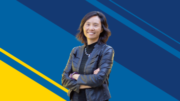 Asian American woman smiling with arms crossed standing against UCI blue and gold background