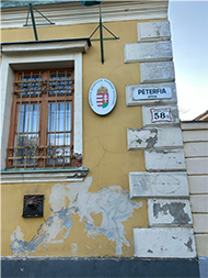 photo of side of building with yellow wall, white brick and street sign in Hungarian
