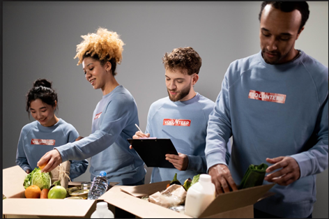 Four adults in blue long-sleeve tee shirts packing food boxes