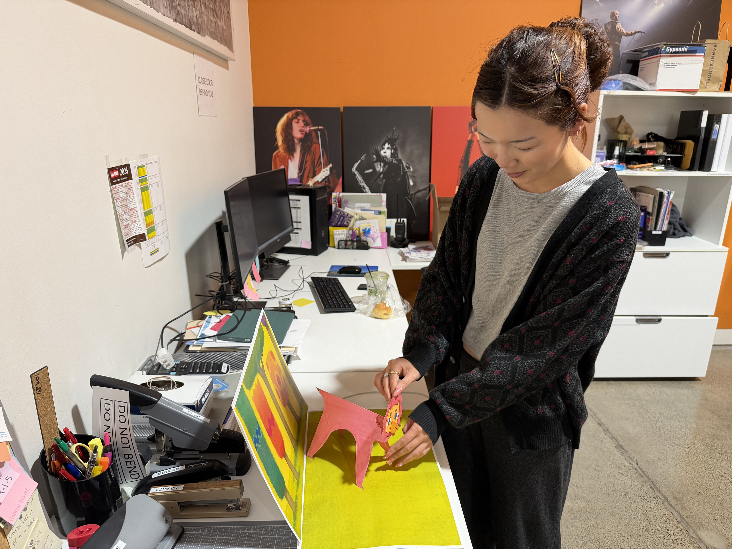 Student intern Arianna Louie is holding a paper lion and helping put together art for an exhibition. 