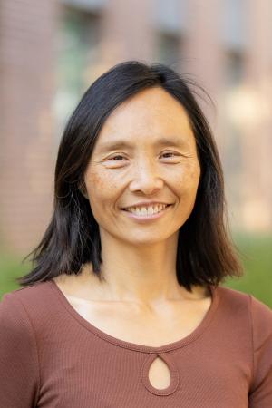 Smiling woman with dark shoulder length hair wearing brown top