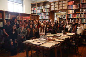 A group of students stands among a library of books.