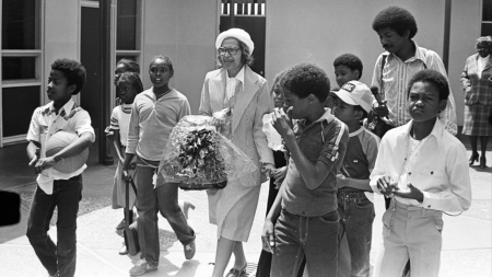 Black and white photo of Rosa Parks with students at Oakland Community School