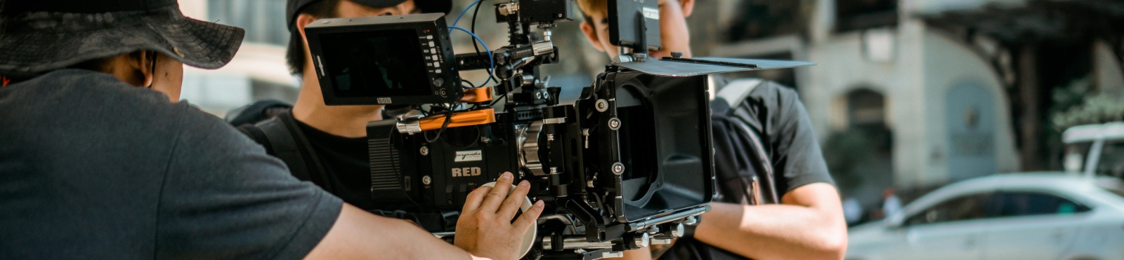 A crew of people hold a camera