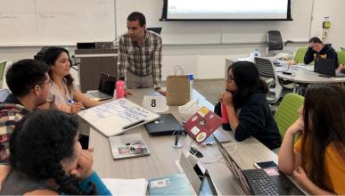 Spanish Professor Julio Torres instructs a group of students sitting at a table