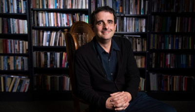 Professor Borucki sitting in front of bookshelves, smiling.